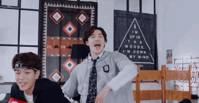 two young men are dancing in a room with a sign that says i 'm up in the woods