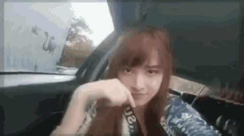 a woman is sitting in the back seat of a car with her hand on her chin .