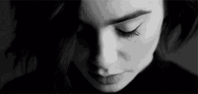 it is a black and white photo of a woman 's face with her eyes closed .