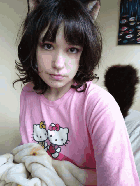 a girl wearing a pink hello kitty shirt has a cat ear on her head