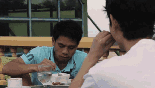 a man in a blue polo shirt with the letter u on it is eating