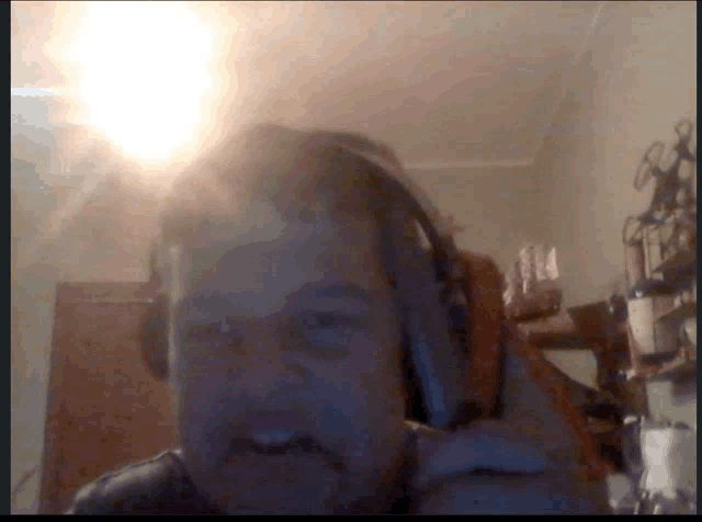 a man wearing headphones looks at the camera with a light behind him