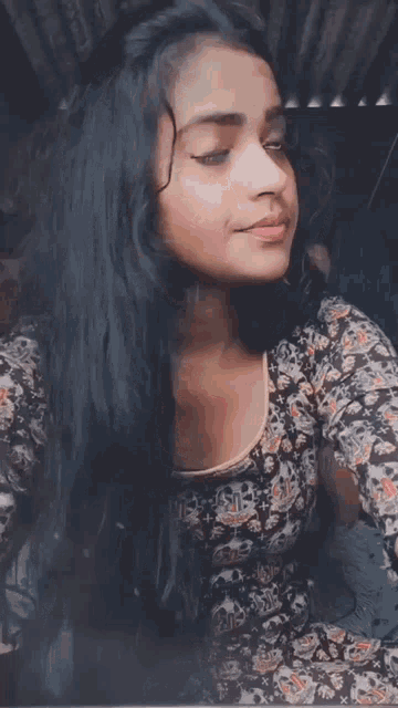a woman with long black hair is wearing a floral top and making a funny face