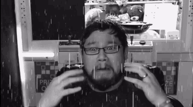 a man with glasses and a beard is sitting in front of a machine that says prize