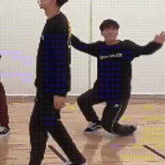 a couple of men are standing next to each other on a wooden floor in a room .