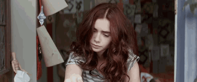 a woman with red hair is holding a piece of paper with the letter s on it