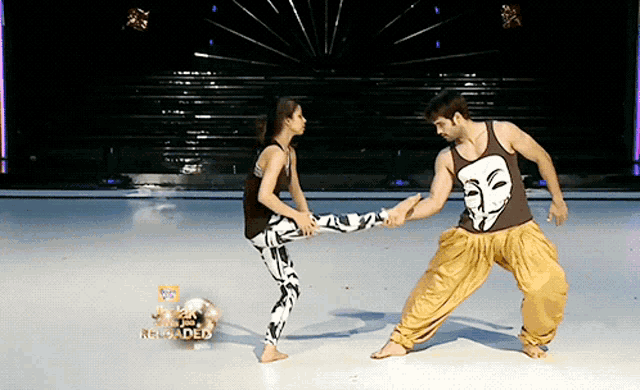 a man in a tank top with a mask on it holds a woman 's leg while dancing