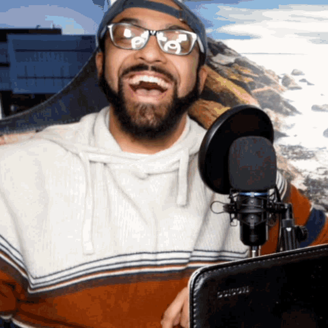 a man wearing glasses and a hat is sitting in front of a microphone with a case that says ' samsung '