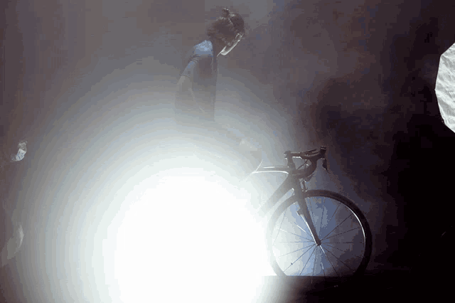 a person riding a bike in the dark with a light behind them