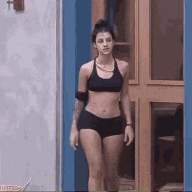 a woman in a bikini top and shorts is walking out of a doorway