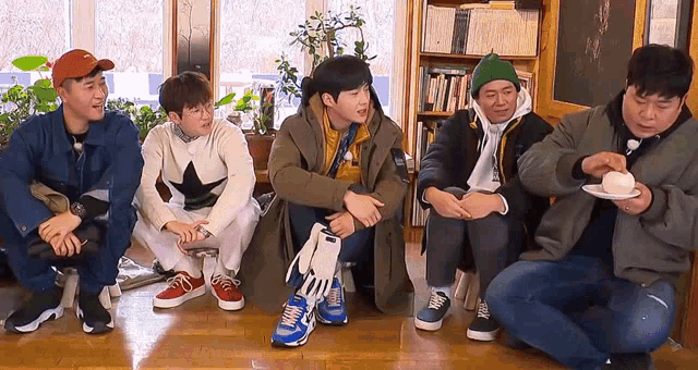 a group of men are sitting on the floor in a room eating food .