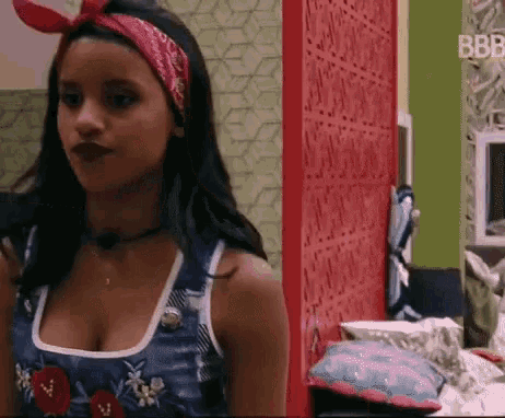 a woman wearing a red headband and a blue tank top is standing in a room .