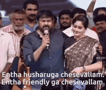 a man is holding a microphone in front of a crowd of people and talking to a woman .