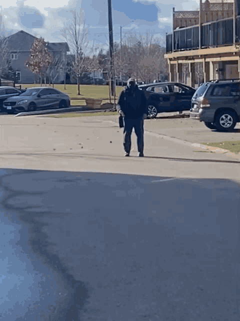 a man wearing a mask walks down a parking lot