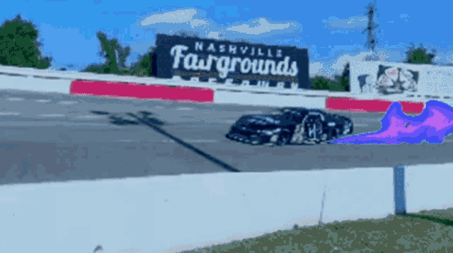 a race car is on a track with a nashville fairgrounds sign in the background