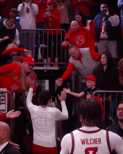 a basketball player wearing a wilcher jersey stands in front of a crowd