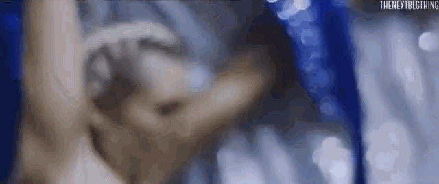 a close up of a person 's face with a blue background and a blurred background .