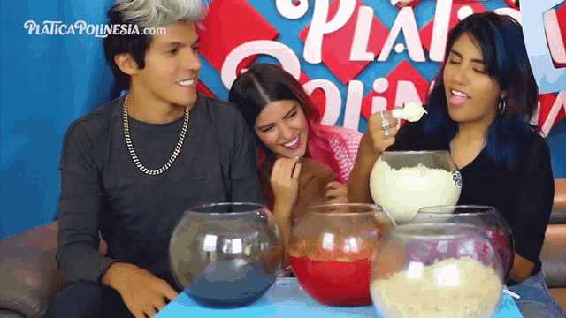 a group of people sitting at a table with bowls of food in front of a sign that says " platica polinesia "