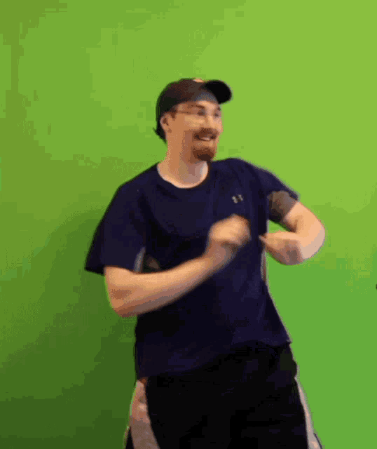 a man in a blue under armour shirt is dancing in front of a green background