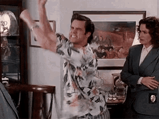 a man in a hawaiian shirt is dancing in a living room .