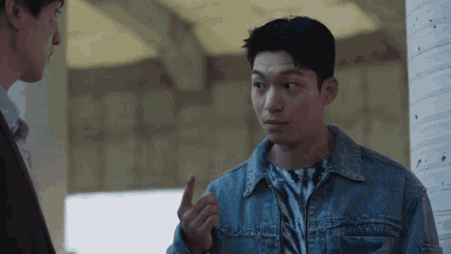 a man in a denim jacket is pointing at something