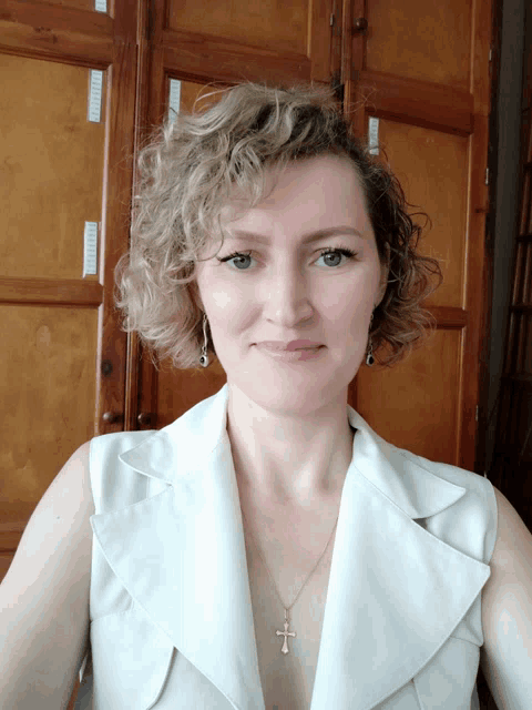 a woman wearing a white shirt with a cross necklace