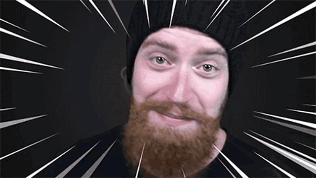 a man with a beard wearing a black hat looks at the camera