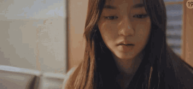 a close up of a woman 's face with a sad look on her face in a room .