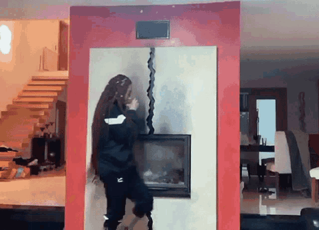 a woman with long hair is standing in front of a fireplace in a living room ..