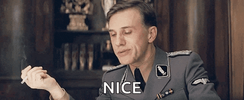 a man in a military uniform is smoking a cigarette and saying nice .