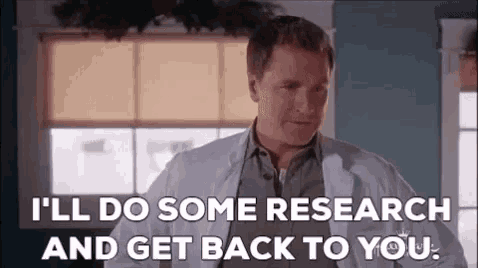 a man in a lab coat is standing in front of a window and saying `` i 'll do some research '' .