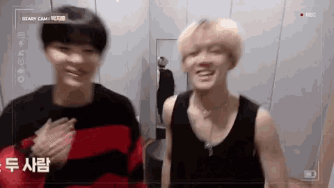 two young men are standing next to each other in a room with a camera .