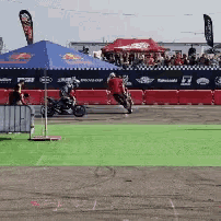 a man is riding a motorcycle on a track in front of a red bull tent