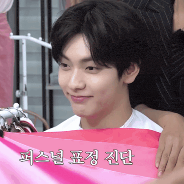 a person holding a pink piece of cloth with korean writing on it