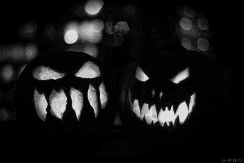 a black and white photo of two carved halloween pumpkins with glowing faces