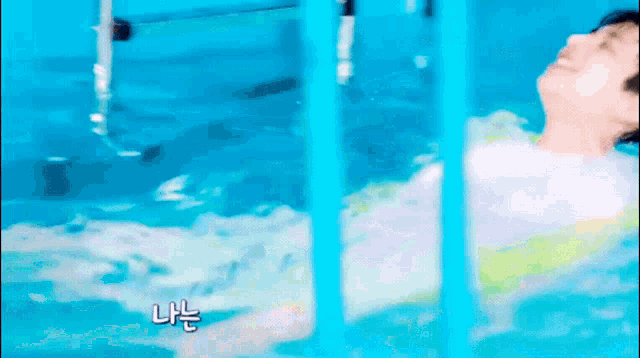 a man is laying in a swimming pool with chinese writing on the bottom of the screen .