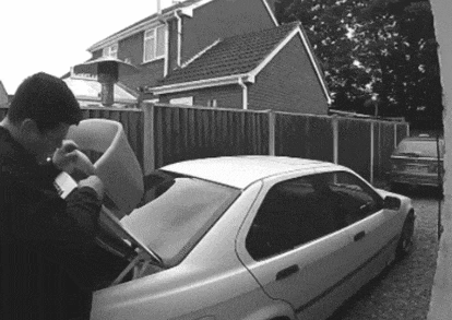 a man opens the trunk of a car in front of a house