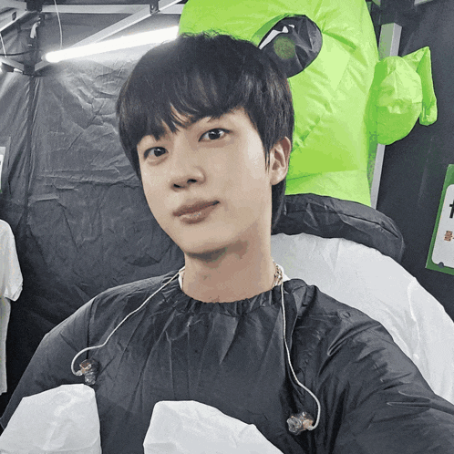 a young man taking a selfie with a green inflatable alien