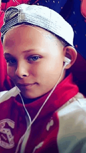 a young boy wearing headphones and a hat is sitting in a bus .