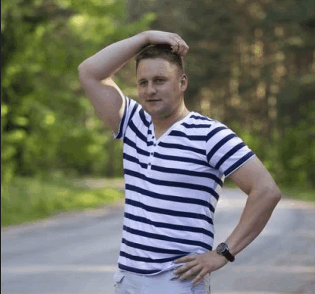 a man in a blue and white striped shirt is scratching his head