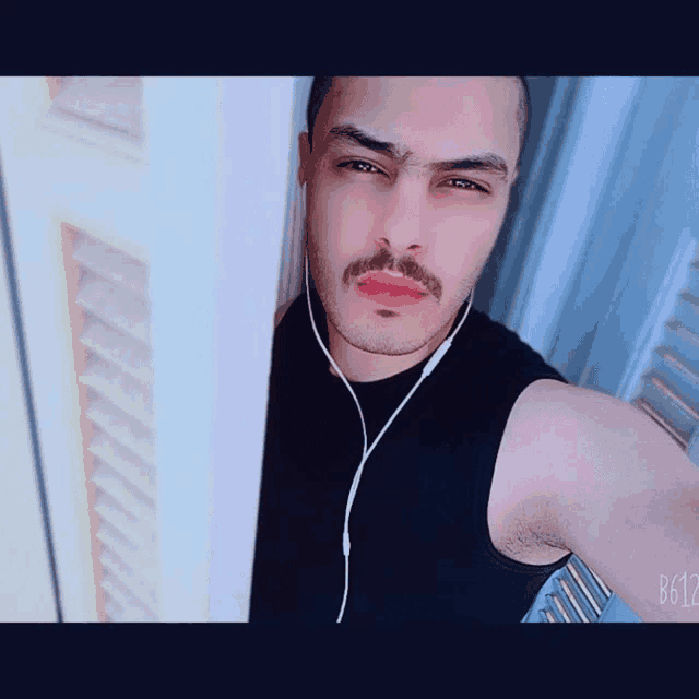 a man with a mustache is wearing headphones and taking a picture of himself
