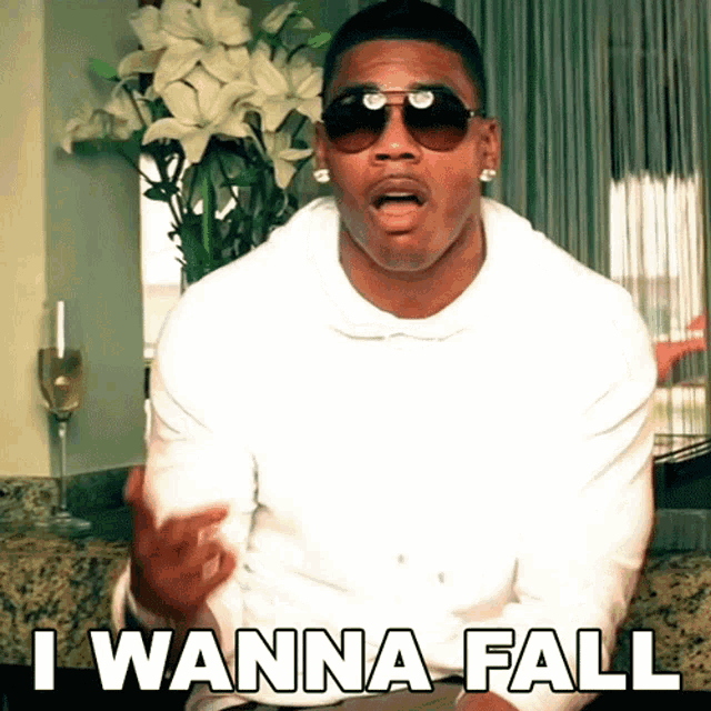 a man wearing sunglasses says " i wanna fall " in front of flowers