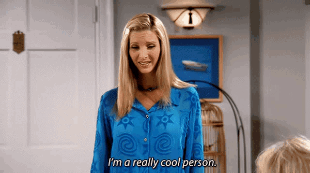 a woman in a blue shirt is standing in a room and saying i 'm a really cool person .