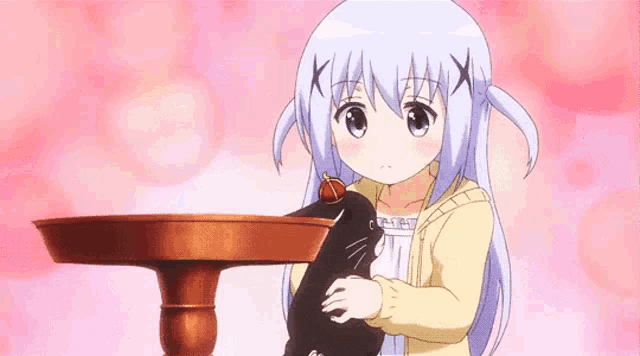 a little girl is holding a black cat in her arms .