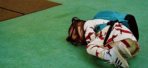a woman is laying on her stomach on the floor with a backpack on her back .