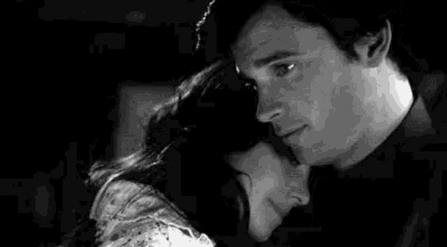 a black and white photo of a man and a woman hugging and kissing .