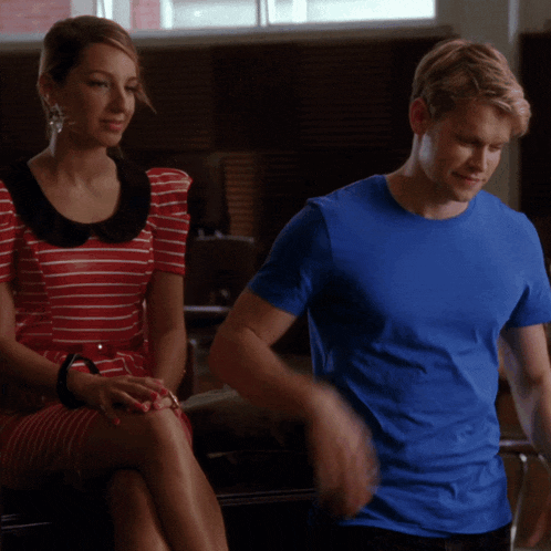 a man in a blue shirt sits next to a woman in a striped dress