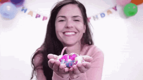 a woman is holding a cupcake in her hands and blowing out candles .