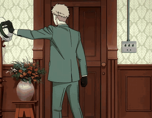 a man in a suit is standing in front of a door and holding a hat