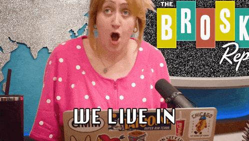 a woman holding a laptop with the words we live in on it